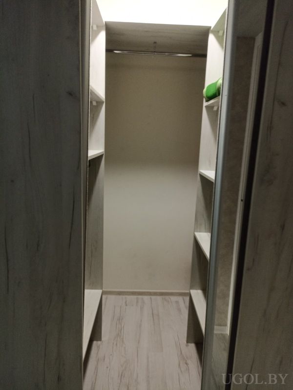 Узкое помещение с деревянными полками, местом для хранения и штангой для подвешивания одежды.