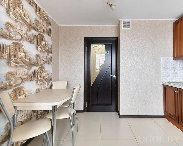 Зона с чёрной дверью с матовым стеклом, столом на четыре персоны и обоями с архитектурным узором.