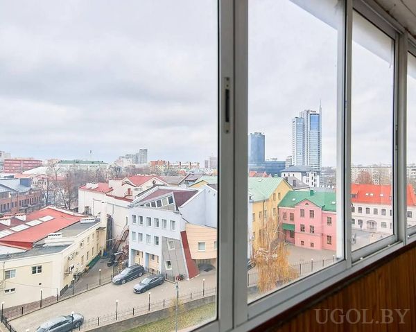 Городской пейзаж с разноцветными домами, башнями и контрастом между старой и современной архитектурой.