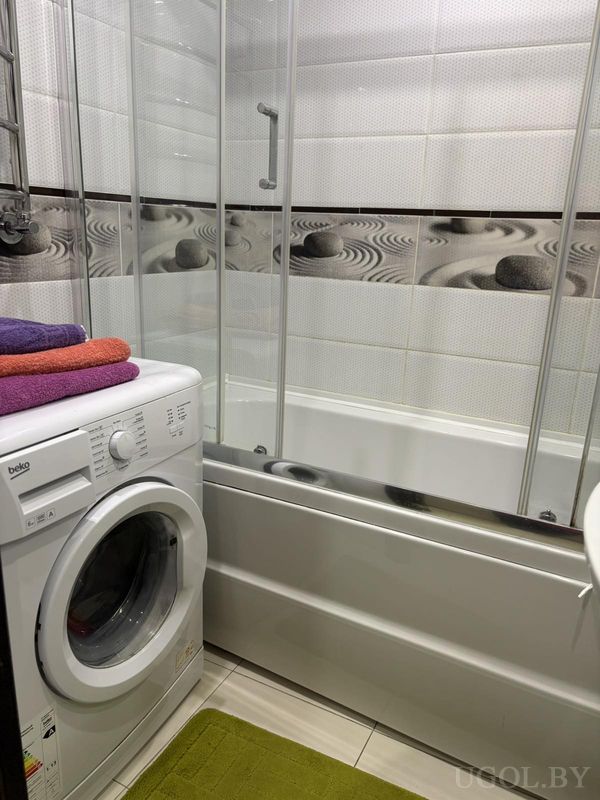 Ванная с машинкой beko, цветными полотенцами, стеклянной перегородкой и декоративной плиткой.