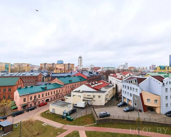 Панорама с домами с зелёными и красными крышами, башней и архитектурным контрастом.