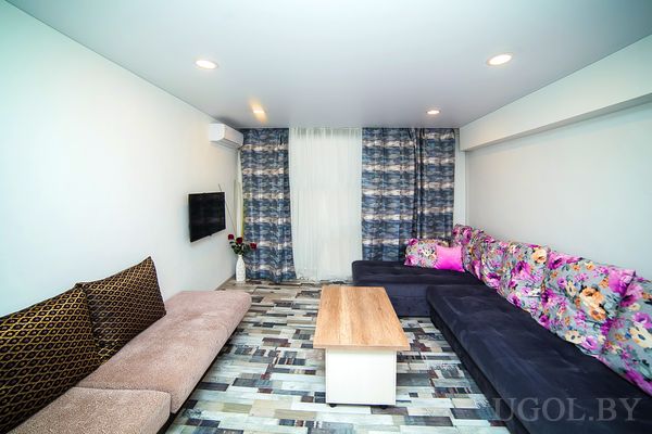 Интерьер с диванами, столом, телевизором, вазой, шторами и плиткой с узором.