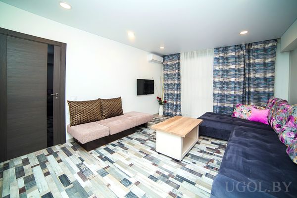 Комната с диваном, столом, телевизором, вазой, шторами и плиткой с орнаментом.