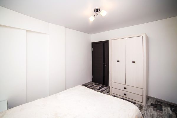 Комната с кроватью, шкафом, дверью, светильником и плиткой с узором.