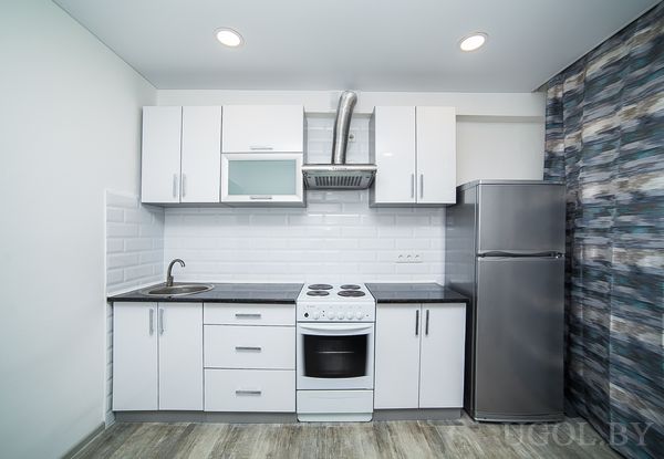 Интерьер с плитой, вытяжкой, мойкой, холодильником, столом и декоративной отделкой.