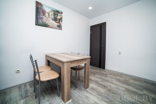 Комната с столом, стульями, дверью, плиткой и настенным декором.