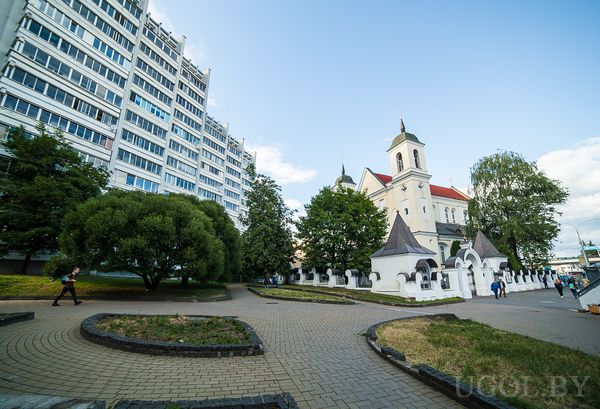 Уличная сцена с церковью, небоскрёбом, дорожками, людьми и декоративным забором.