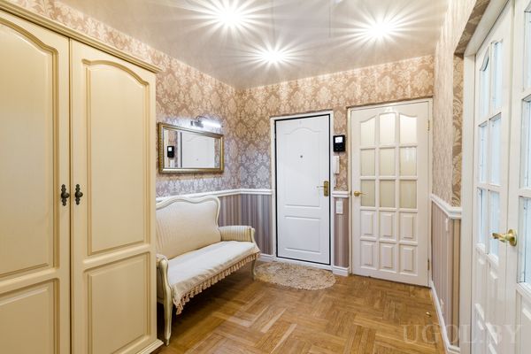 Зона входа с банкеткой, зеркалом, шкафом, дверями, светильником и классической отделкой.