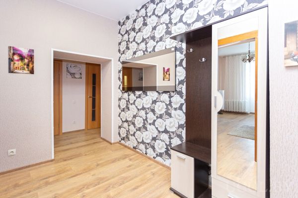 Прихожая с мебелью в тёмном и белом цвете, зеркалом, вешалкой и стеной с крупными белыми розами.