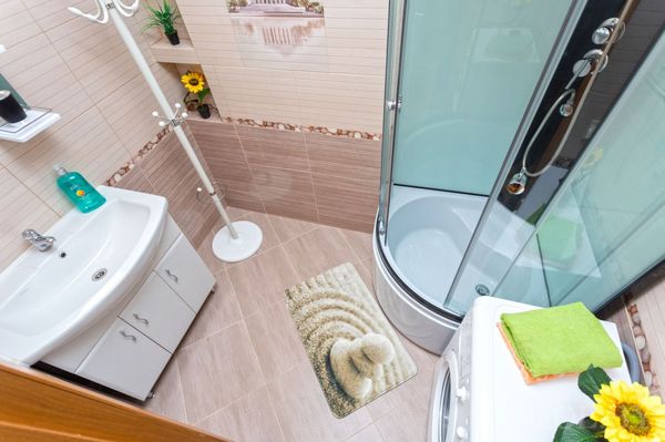 Современная ванная с душевой кабиной, раковиной, стиральной машиной и полкой с полотенцами.