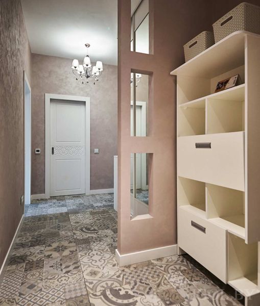 Плитка с орнаментом, белая дверь, зеркальные вставки и люстра в интерьере с мягким розовым оттенком.