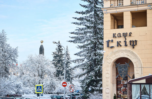 Снежные деревья, машины, здание с вывеской «кафе Скіф» и памятник с золотой звездой на фоне.