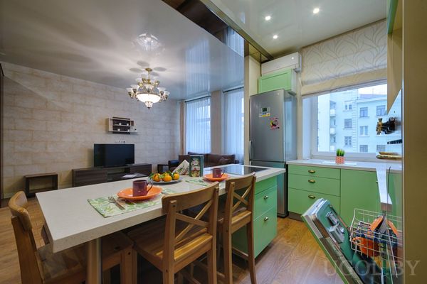 Мятные шкафы, открытая посудомоечная машина, остров с сервированными местами и фруктами, вид на соседние дома.