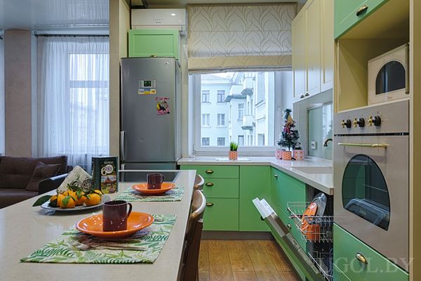 Мятно-белая кухня с ёлкой, розовыми контейнерами, островом с сервировкой и видом из окна.