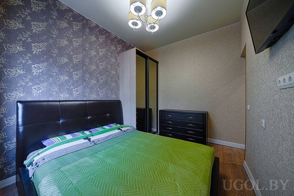 Два дивана, зелёные ковры, кухня с мятными шкафами, зеркальная стена и элегантные люстры.