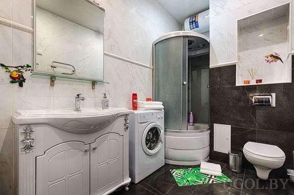 Белая тумба, зеркало, душевой уголок, стиральная машина, водонагреватель и наклейки с птицами.