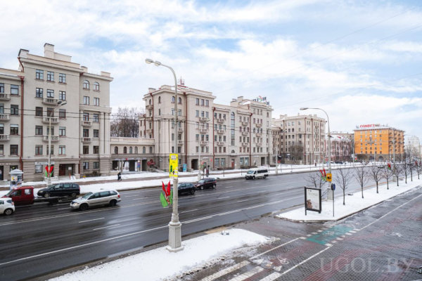 Многоэтажные дома, дорога со снегом, остановка, баннеры на столбах и магазин «Гиппо» на фоне.