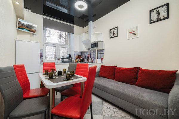 Кухня с обеденной зоной на шесть человек, серым диваном и зимним пейзажем за окном.