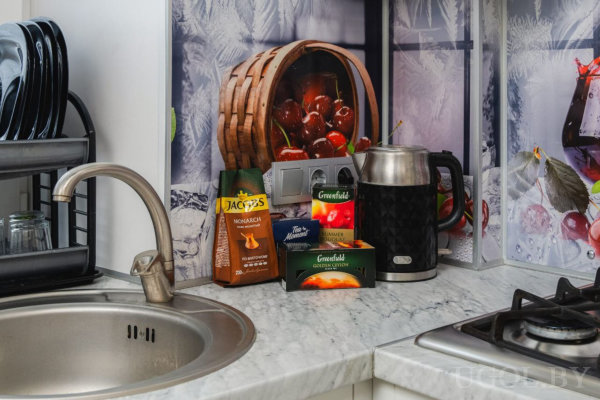 Кухонная зона с посудой, напитками и декоративным фартуком с зимними вишнями.