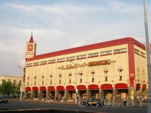 Главный универмаг города, красно-бежевый фасад, башня с часами, арки, активное движение, центр столицы.