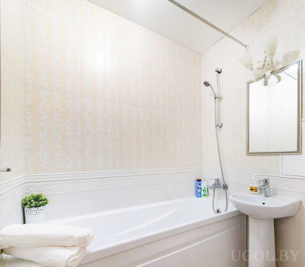 Интерьер с ванной, умывальником, растением, полотенцами, светильником и декоративной отделкой.