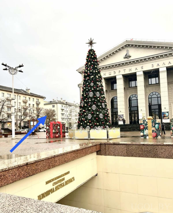 Городская сцена с ёлкой, колоннами, праздничным декором и входом в книжный магазин.