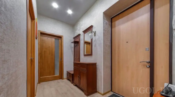 Светлая прихожая с входной дверью, классическим гарнитуром с зеркалом и крючками, двумя межкомнатными дверями и точечным освещением.