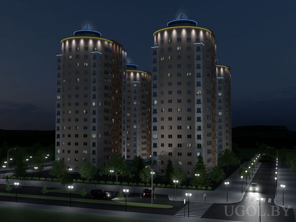 Четыре цилиндрических многоэтажных дома с голубой подсветкой и светящимися треугольными элементами на крышах, освещённые окнами и уличными фонарями, вокруг ухоженные деревья, кусты и парковка с машинами.