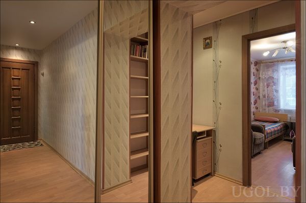 Просторный холл с зеркальным шкафом, встроенной полкой и переходом в спальню и рабочую зону. Обои с геометрией и винтажный свет.