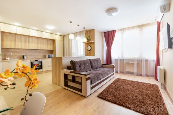 Современная студия с кухней, диваном и обеденной зоной у окна