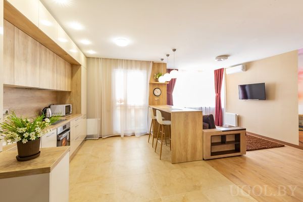 Кухня с деревянным гарнитуром, обеденным столом и телевизором в гостиной