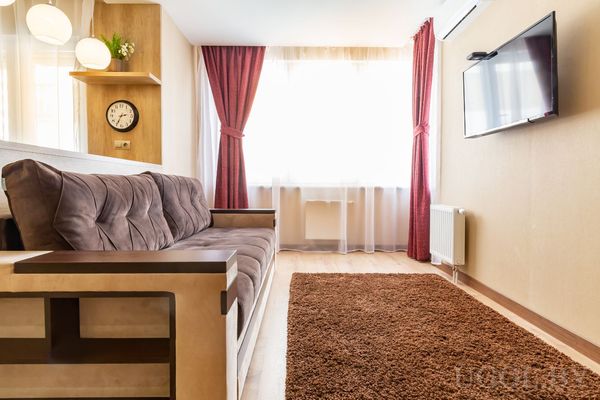 Гостиная с диваном, ковром и большим окном с красными шторами