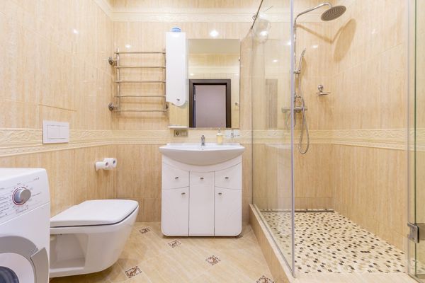 Современный санузел с душевой кабиной, стиральной машиной и умывальником