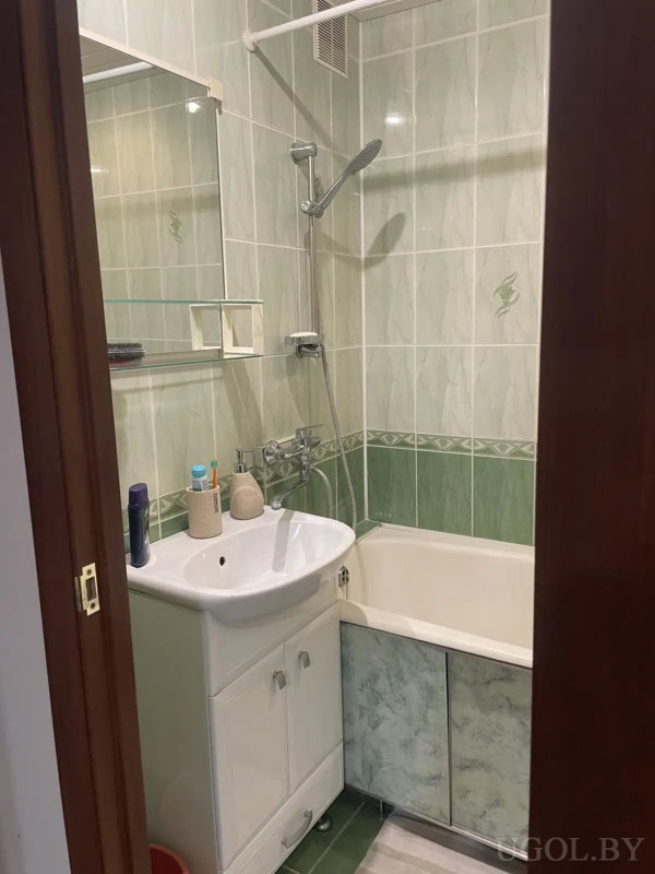 Небольшой санузел с белым унитазом, коричневыми плитками и двумя люками над бачком.