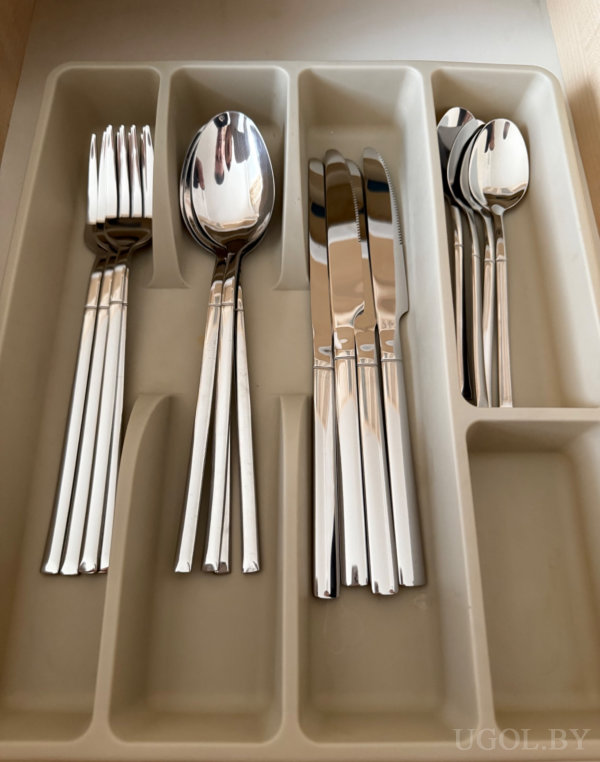 Организованный кухонный ящик с вилками, ложками, ножами и чайными ложками в отдельных секциях.