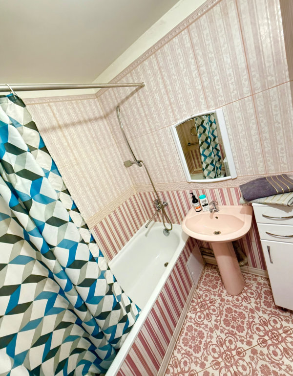 Розовая раковина, ванна и плитка с цветочным узором создают атмосферу винтажного санузла.