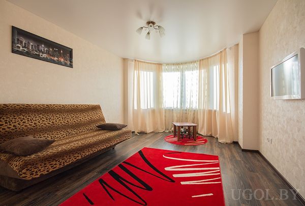 Современная гостиная с леопардовым диваном, красным ковром, круглым столиком и видом из окна.