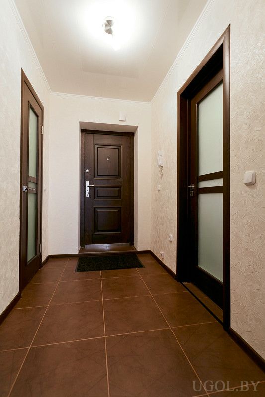 Уютная прихожая с коричневой плиткой на полу и светлыми стенами.