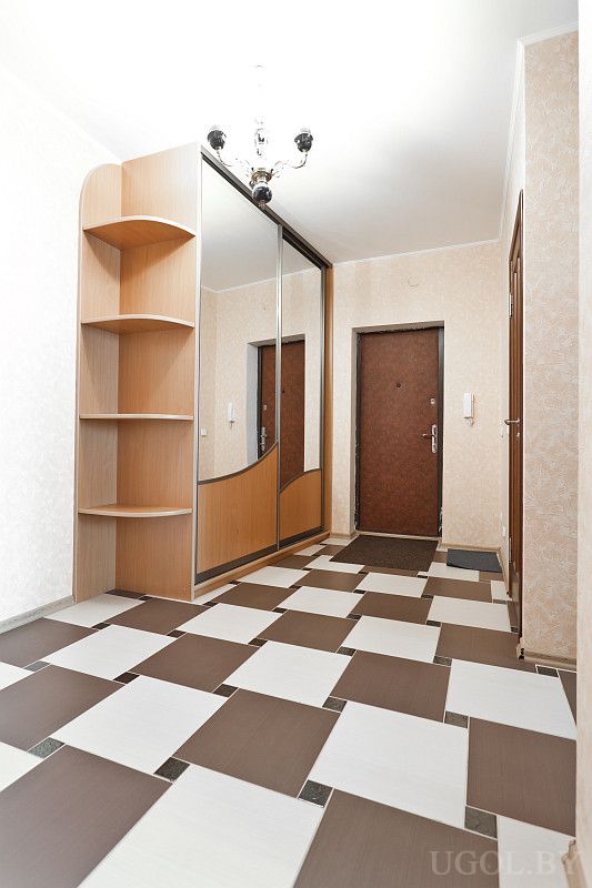 Чистая входная зона с зеркальным шкафом, полками и плиткой. Светлая отделка, межкомнатные двери и домофон.