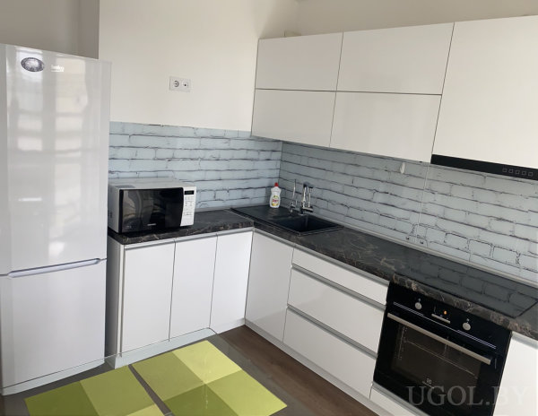 Рабочая зона с плитой, раковиной, микроволновкой, холодильником и зелёной плиткой на полу.