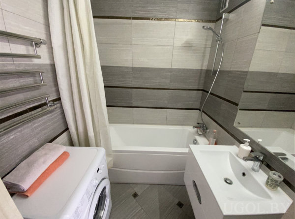 Комната с ванной, душем, умывальником, машиной, зеркалом и серой плиткой.