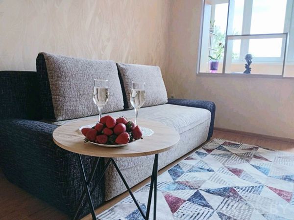 Современная гостиная с тёмным диваном, круглым столиком, двумя бокалами и тарелкой клубники.