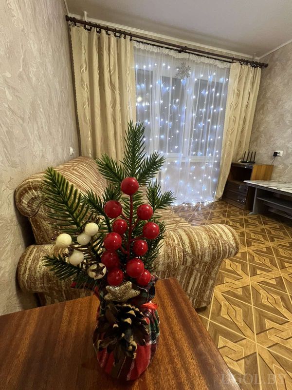 Праздничная композиция с еловыми ветками, ягодами, шишками и звёздочкой в клетчатом контейнере.