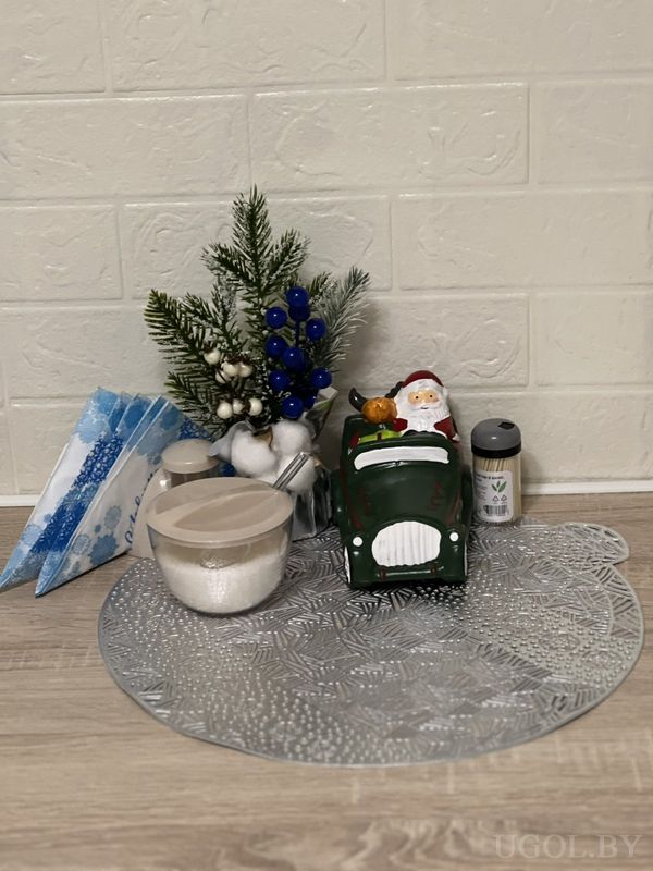 Сервировка с Сантой в зелёной машине, хлопком, специями и салфетками на серебристой подставке.