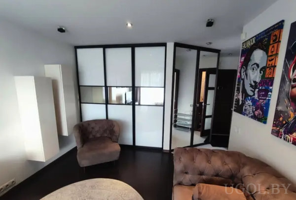 Современная гостиная с коричневыми креслами, стеклянной перегородкой и ярким портретом «Сальвадора Дали» на стене.