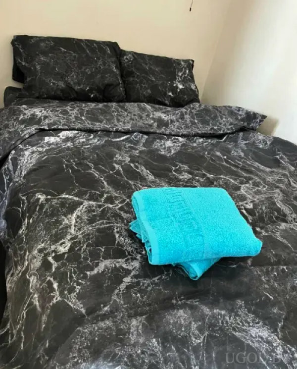 Минималистичная комната с черно-белым постельным бельем и ярким акцентом в виде бирюзового полотенца.