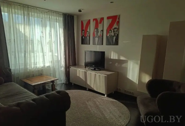 Светлая комната с темной мебелью, телевизором и тремя картинами с мужчинами в костюмах на фоне красных элементов.