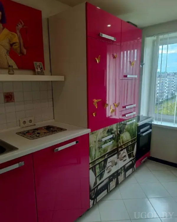 Яркая кухня с розовыми шкафами, изображением природы и видом на город через большое окно.