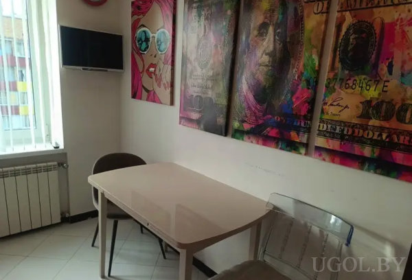 Интерьер с глянцевым столом, картинами в стиле поп-арт, включая «Бенджамина Франклина» и женщину в очках.