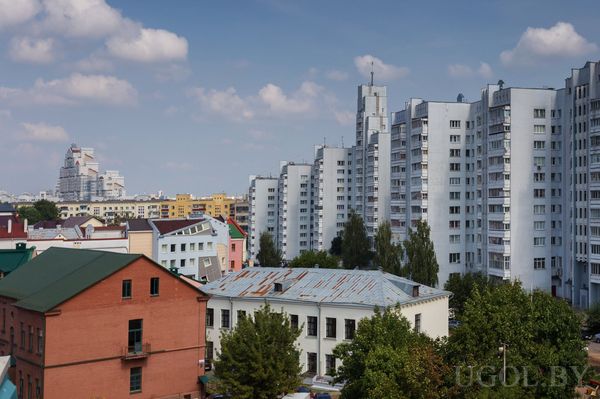 Городской пейзаж с низкими старыми домами на переднем плане и современными высотками на фоне.